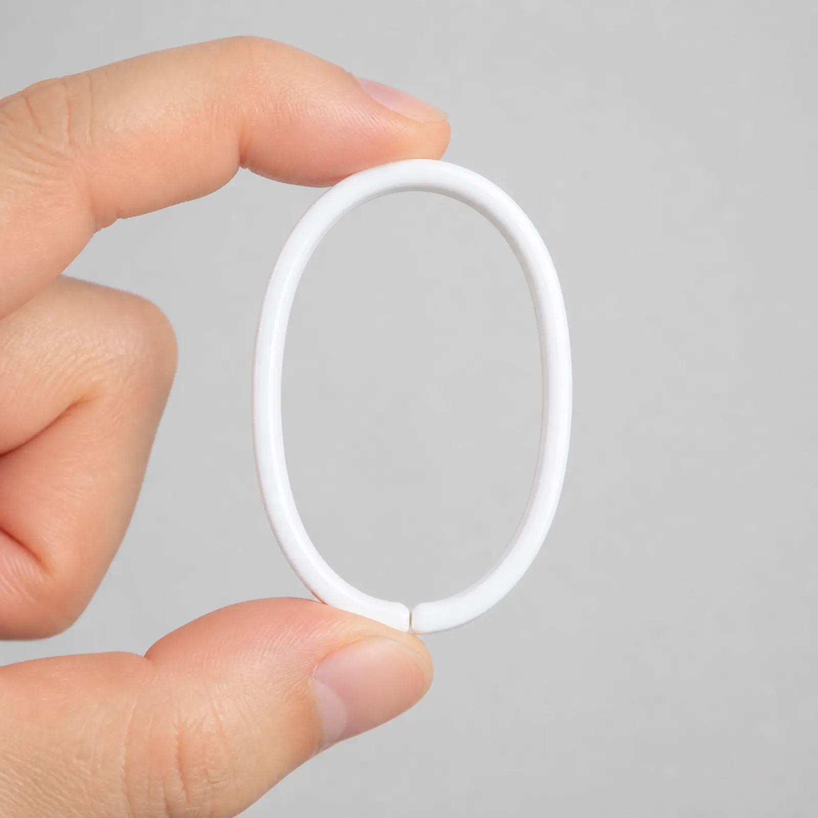 Gancho blanco para cortina de 6 x 3,7 cm sostenido en la mano