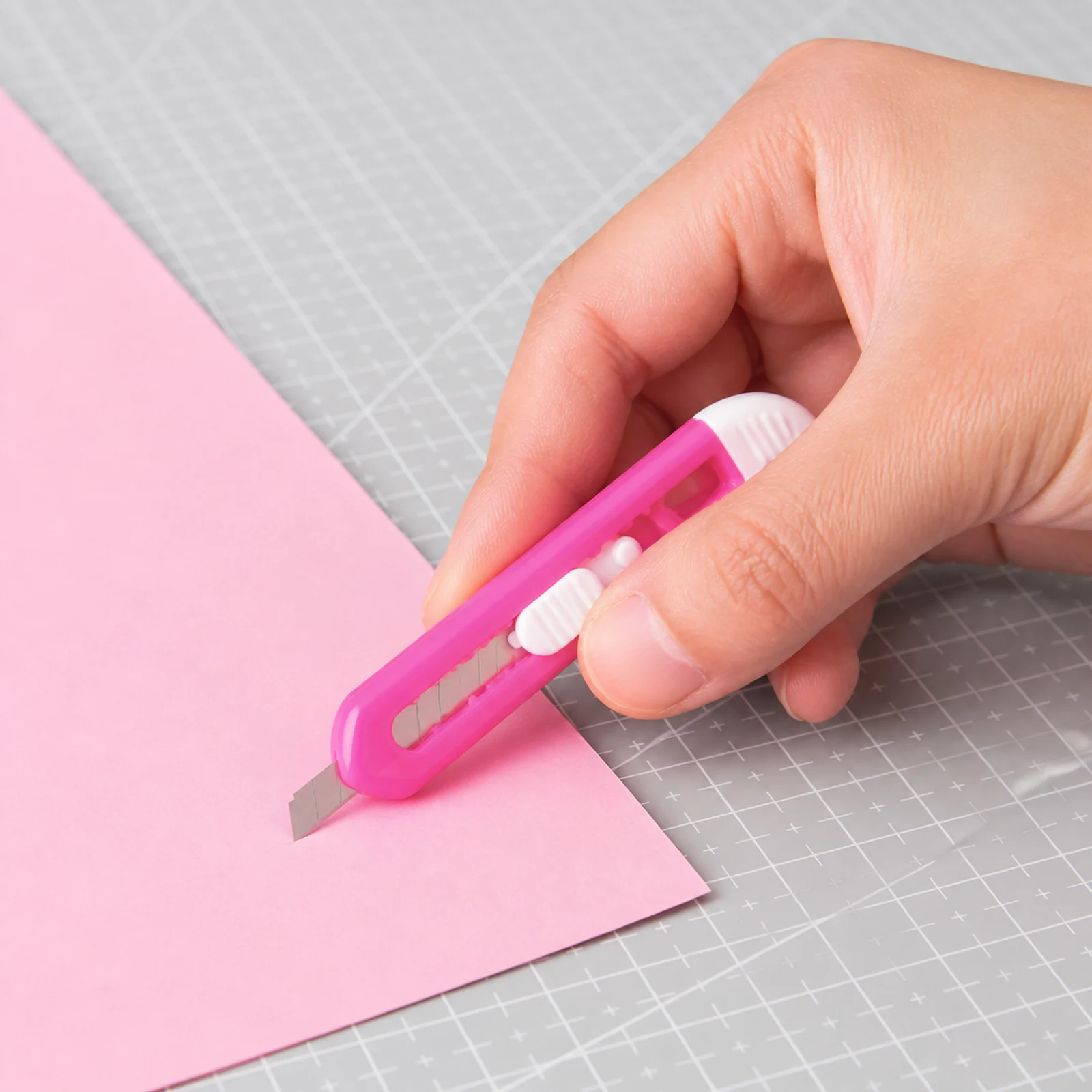 Mini cortacartón rosado cortando papel sobre base de corte