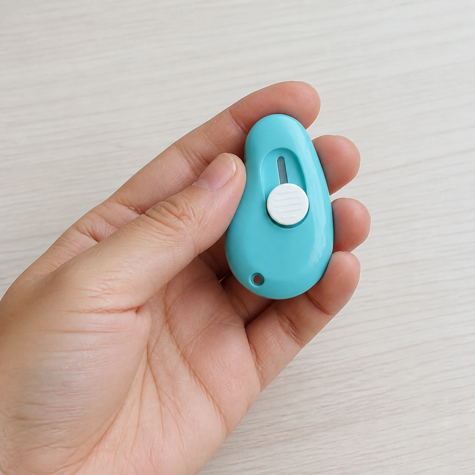 Mini cortador de seguridad azul de 6 por 3,8 cm sostenido en una mano