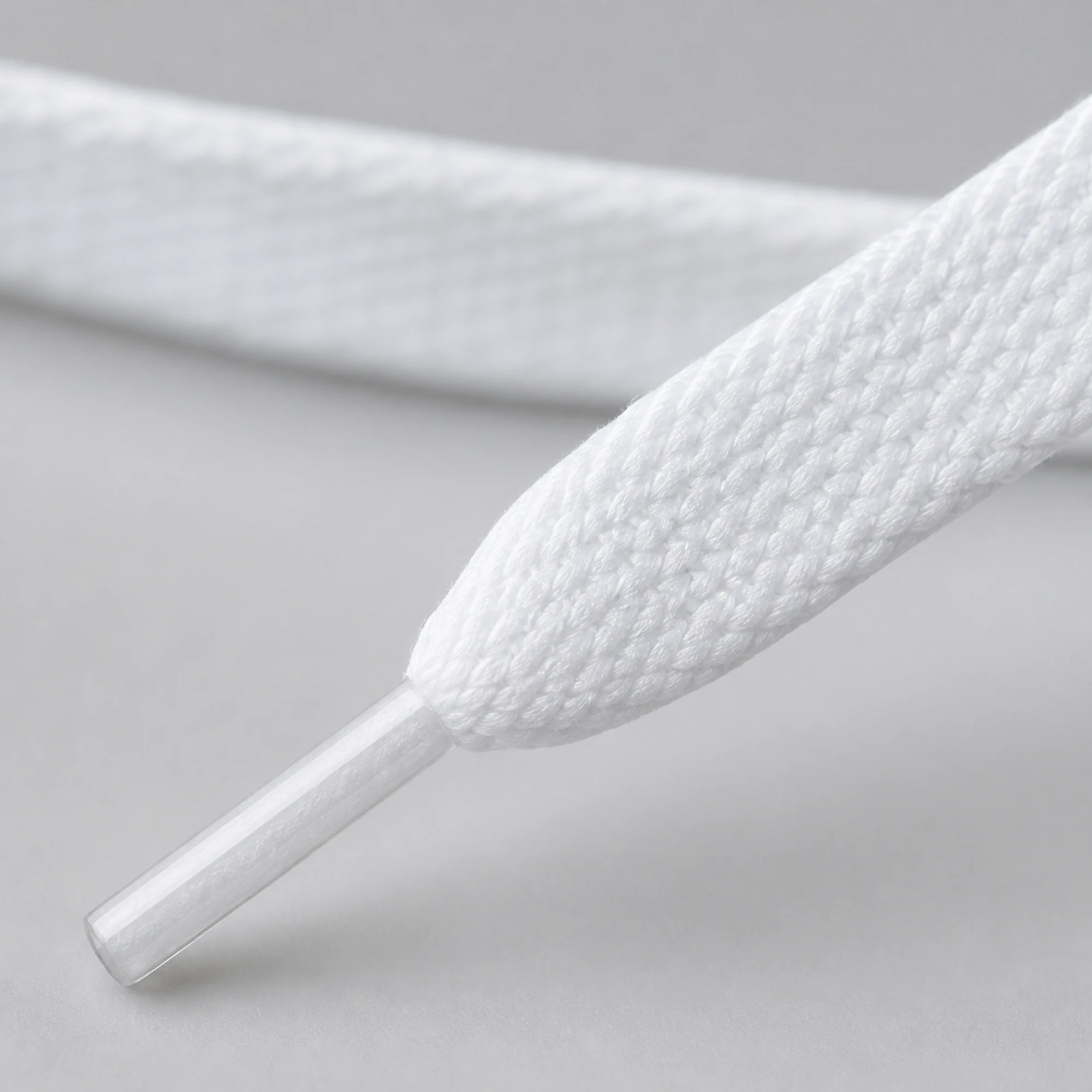 Detalle del tejido plano blanco y punta transparente del cordón