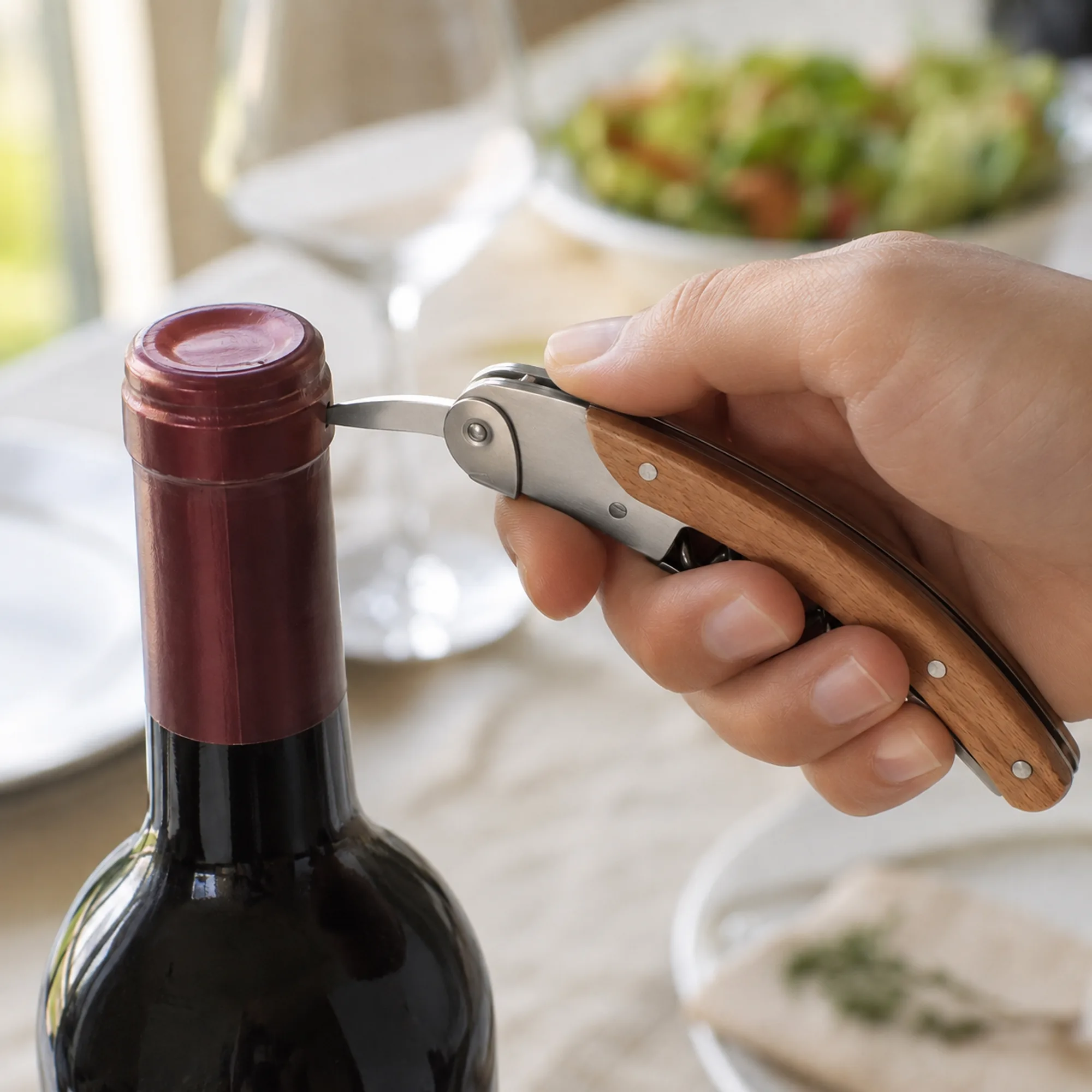 Cortacápsulas plegable retirando la cubierta de una botella de vino